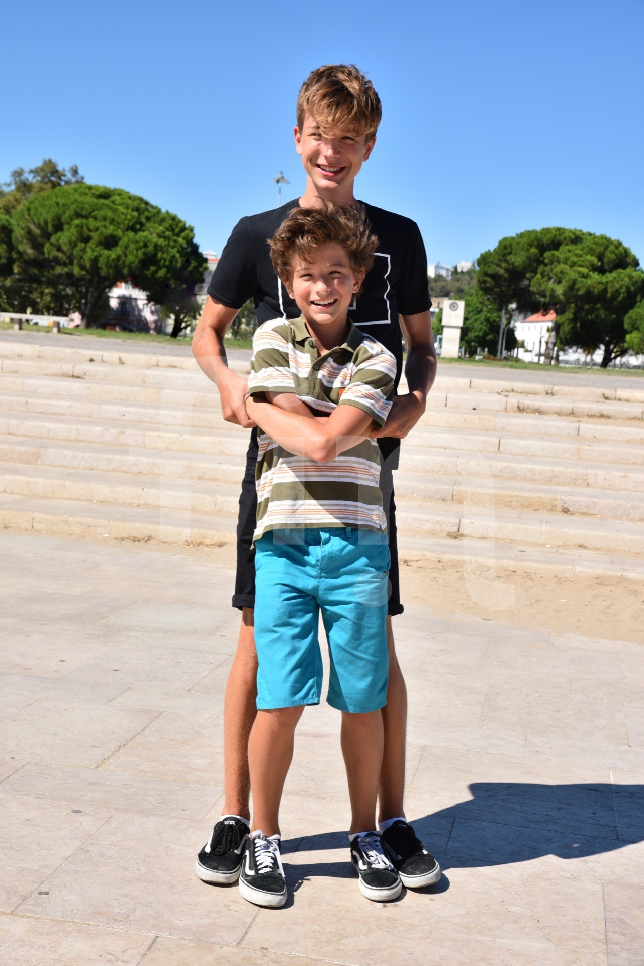Smiling brothers looking in camera are playing on the sun
