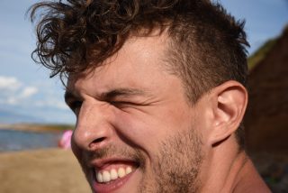 Happy guy close up on beach winking