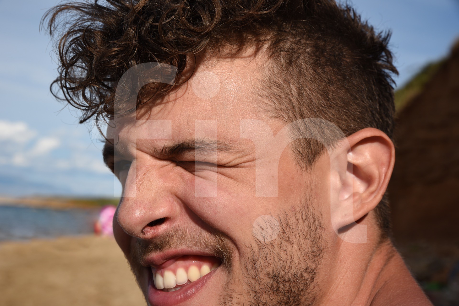 Happy guy close up on beach winking
