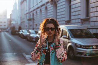 Street style fashion girl with a sunglasses looking front high key cars parked