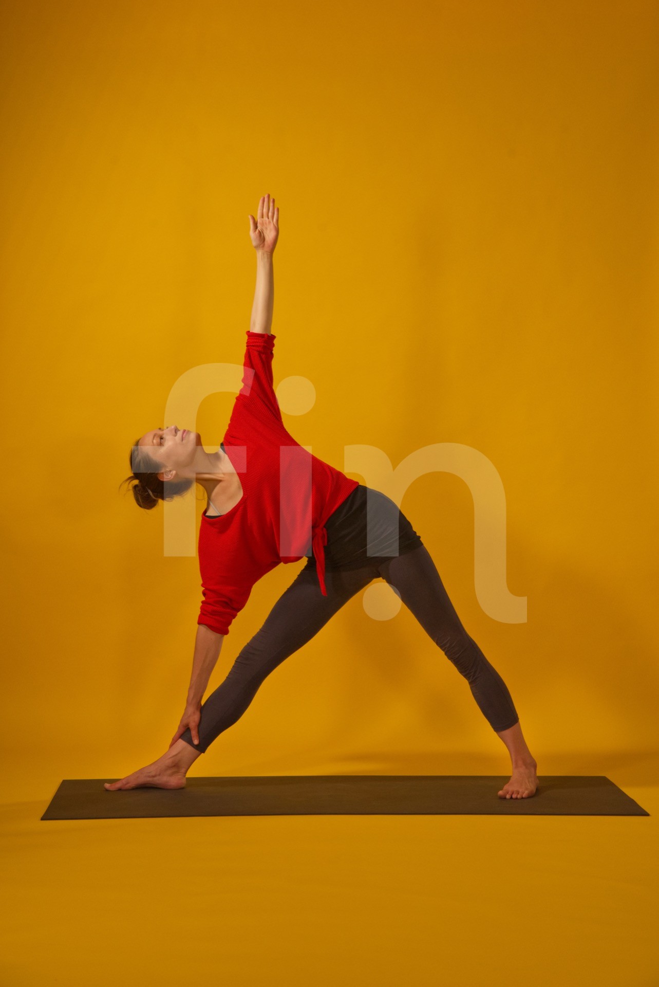 women in orange shirt on mat do yoga pose trikonasana isoleted on yellow background