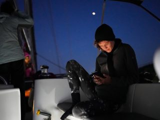 Lady watching in phone on sailsboat at dusk