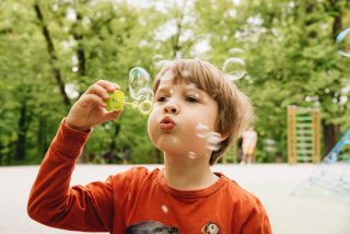 Little boy blows soap bubbles on a playground