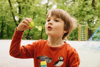 Little boy blows soap bubbles on a playground